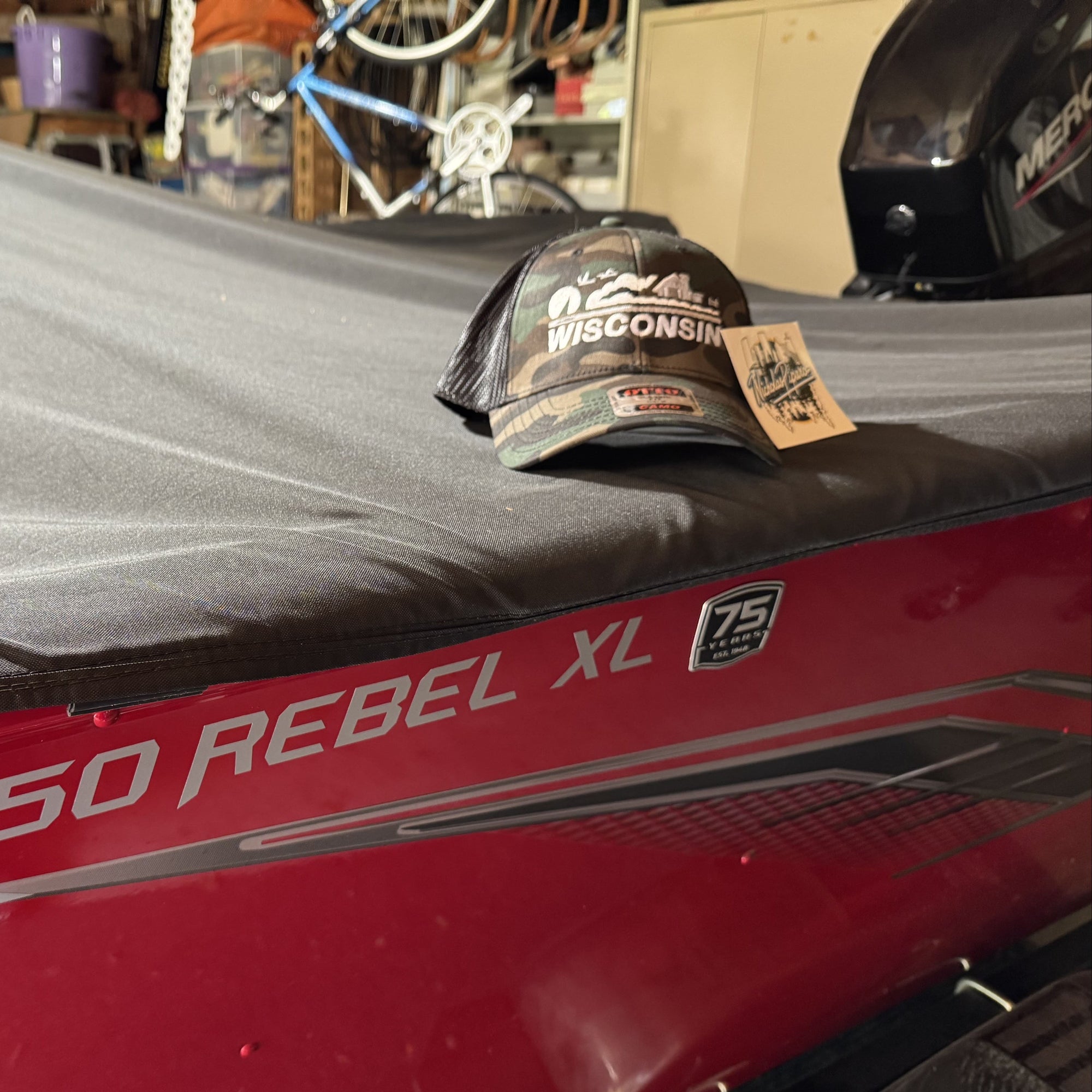 Red outboard motor with a wisconsin cap on top, indoors.