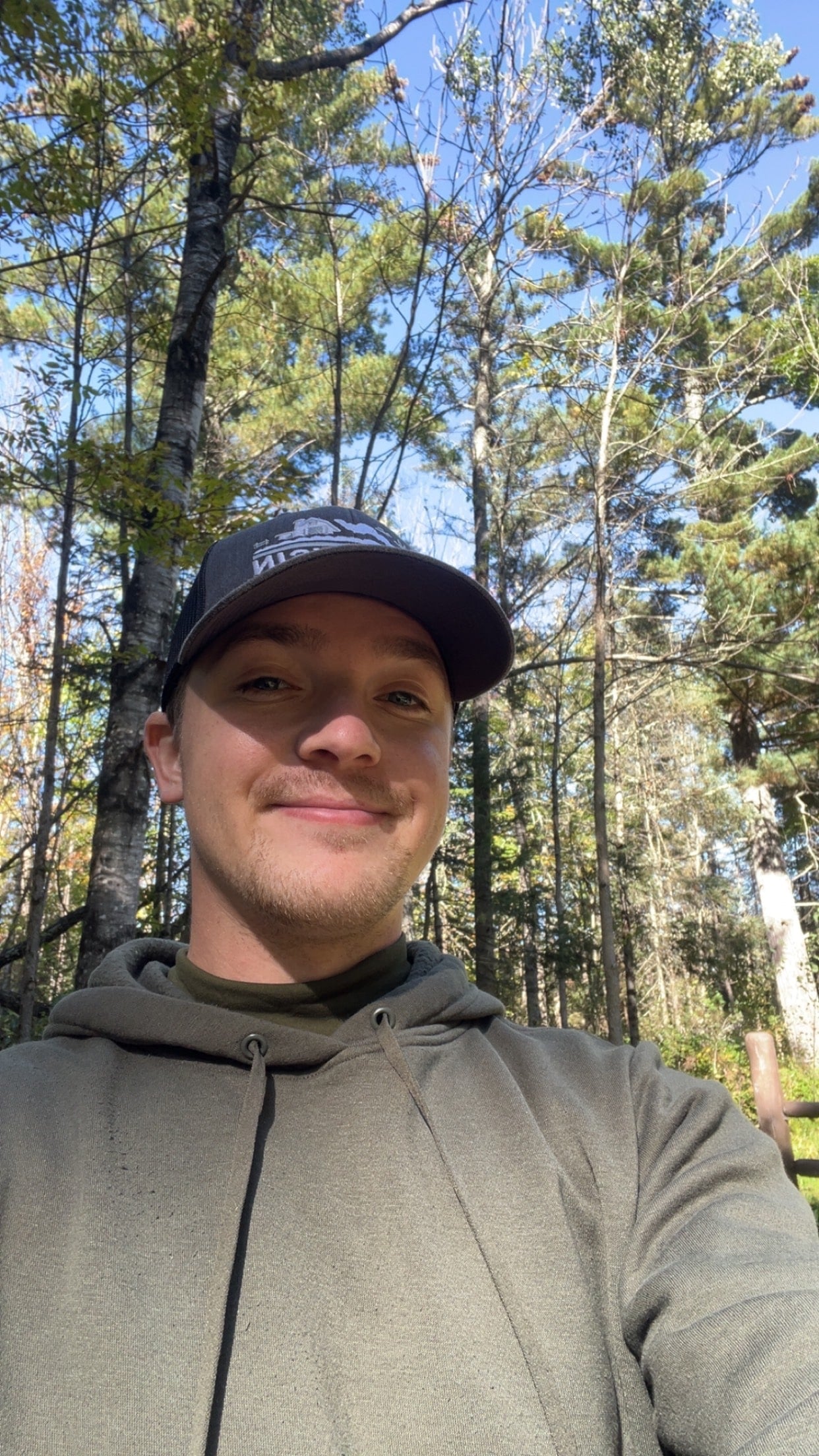 Person wearing a cap and hoodie standing in a forest